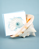 Quilled Abstract Nautilus Greeting Card in front of a blue background, inside of a seashell.