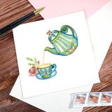 Quilled Afternoon Tea greeting card laying flat on a paper insert with a pen atop a wood background with American flag stamps beneath it.