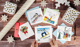  Quilled Backcountry Snowboarder Greeting Card on wooden tabletop surrounded by quilled greeting cards, wrapping paper and decorative snowflakes