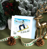  Quilled Backcountry Snowboarder Greeting Card surrounded by christmas decorations in front of green background