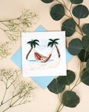 Quilled Beach Hammock Greeting Card on beige background with light blue envelop next to eucalyptus and baby's breath