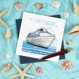 Quilled Cruise Ship Greeting Card with navy envelope on top of swirly blue background surrounded by seashells