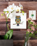 Quilled Decorative Owl Greeting Card on wooden wall next to white orchid and mini hanging plant gift enclosure quilled card