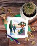 Quilled Desert Landscape Greeting Card laying flat on top of a wood surface, surrounded by a cactus, wax seals, wax stamps, and a pen.