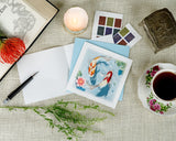 Quilled Koi Fish Pond Greeting Card laying on a linen cloth next to candles, stamps, a teacup, and open book with a flower.