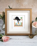 Quilled Mischievous Cat Greeting Card in golden frame surrounded by florals, on white wood table, with beige background
