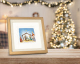 Quilled Nativity Scene Christmas Card in golden frame standing on wooden counter in front of christmas tree with bokeh lights