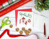 Quilled Red Christmas Ornaments Greeting Card laying on a wooden backdrop next to a bow, scissors, wrapping paper, wax seals, ribbons, a red Classic Lacquer Rollerball Pen.