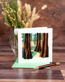 Quilled Redwood Trees Greeting Card with light green envelope and red pen on wooden table in front of dried florals