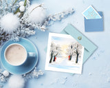 Quilled Snow Covered Trees Greeting Card on snowy background next to snowflake mini gift card and coffee with winter decor