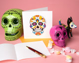 Quilled Sugar Skull Greeting Card with orange envelope in front of insert next to candy and sugar skulls on pink background