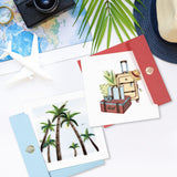 quilled vintage luggage greeting card next to quilled palm tree greeting card on white table next to traveling items