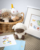 Mini Poppy Sheep Crochet Toy in front of basket of crocheted toys and greeting card in silver frame