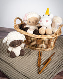 Mini Poppy Sheep Crochet Toy in front of wicker basket filled with crocheted toys next to crochet hooks on brown blanket