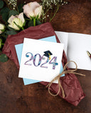 Quilled 2024 Grad Card with light blue envelope on top of flower bouquet 