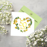 Quilled 50th Wedding Anniversary Card on table with light green envelope surrounded by white flowers
