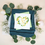 Quilled 50th Wedding Anniversary Card with light green envelope on top of napkin & plate on top of eucalyptus and baby's breath with lace doily