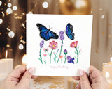 Quilled Birthday Flowers & Blue Butterflies Greeting Card being held in front of candles and confetti.