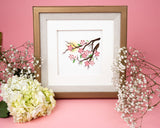 Quilled Cherry Blossoms Greeting Card framed in a Gold Square Artist Series Frame in front of a pink backdrop, surrounded by flowers.
