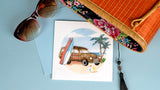 Quilled Classic Woodie Greeting Card laying flat on a light blue background covered by a pair of sunglasses and a camel colored Hand-woven Bamboo Bag.