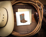 Quilled Cowboy Boots Greeting Card on wooden floor with lasso wrapped around it next to cowboy hat and cowboy boots