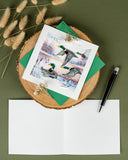 Quilled Duck Migration greeting card with dark green envelope next to card insert and pen on green background