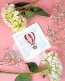 Quilled Heart Air Balloon Greeting Card on pink background with pink envelope  next to white flowers
