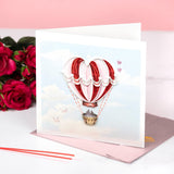 Quilled Heart Air Balloon Greeting Card standing with pink envelope on white table in front of red roses