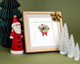  Quilled Holiday Bouquet Greeting Card in gold frame with gold bow next to christmas decorations on green background