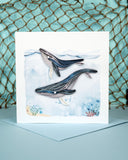 Quilled Humpback Whales Greeting Card standing on blue envelope on blue background with netting in background