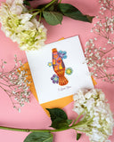 Quilled Love Lava Lamp Greeting Card with orange envelope next to white flowers on pink background