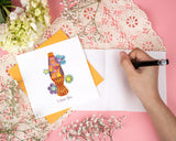 Quilled Love Lava Lamp Greeting Card with orange envelope on top of open insert, lace, pink background, and white flowers