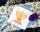 Quilled Modern Menorah Hanukkah Card with blue envelope next to dreidel and candles on white lace next to white flowers