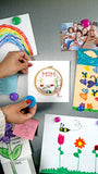 Quilled Mom Cross Stitch Greeting Card being placed on a fridge, surrounded by children drawings and family photos. 