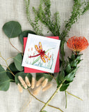 Quilled Red Dragonfly & Cattails Greeting Card with red envelope on top of florals with textured beige background