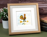 Quilled Rooster Weathervane greeting card in golden frame next to books and flowers in front of wooden background