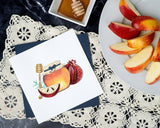 Quilled Rosh Hashanah Greeting Card with navy envelope next to sliced apples and honey on top of lace fabric