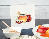 Quilled Rosh Hashanah Greeting Card with navy envelope next to honey and sliced apples on top of lace fabric
