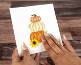 Quilled Stacked Pumpkins Greeting Card being touched by hand with wooden background