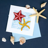 quilled starfish greeting card with blue envelope surrounded by shells on dark blue background