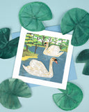 Quilled Two Swans Greeting Card with light blue envelope next to illustrated lily pads on blue background