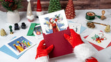 Quilled Vintage Santa Christmas Card coming out of dark red envelope being held by santa over desk of christmas cards and christmas decor
