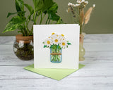 quilled daisy greeting card with green envelope on white wooden background with dried flowers and plant