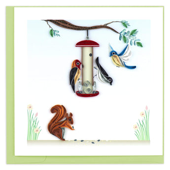 Blank greeting card featuring three quilled birds around a bird feeder hanging from a branch with a squirrel on the ground below