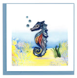 Quilled greeting card of a blue seahorse swimming above the ocean floor 