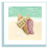 A light brown conch with a pink interior, sitting by the edge of the ocean.