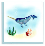 Blank greeting card featuring a quilled blue narwhal swimming over a sandy ocean floor.
