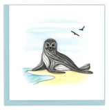 Blank greeting card of a gray ocean seal on sandy coastline