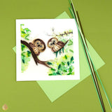 Stylized shot of the quilled owlets greeting card on a green background
