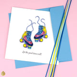 Stylized shot of Quilled Roller Skates Greeting Card on a pink background with paper strips next to it
